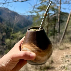 Kalabasa Echo s yerba maté a bombillou držaná v ruke s panoramatickým výhľadom na hory.