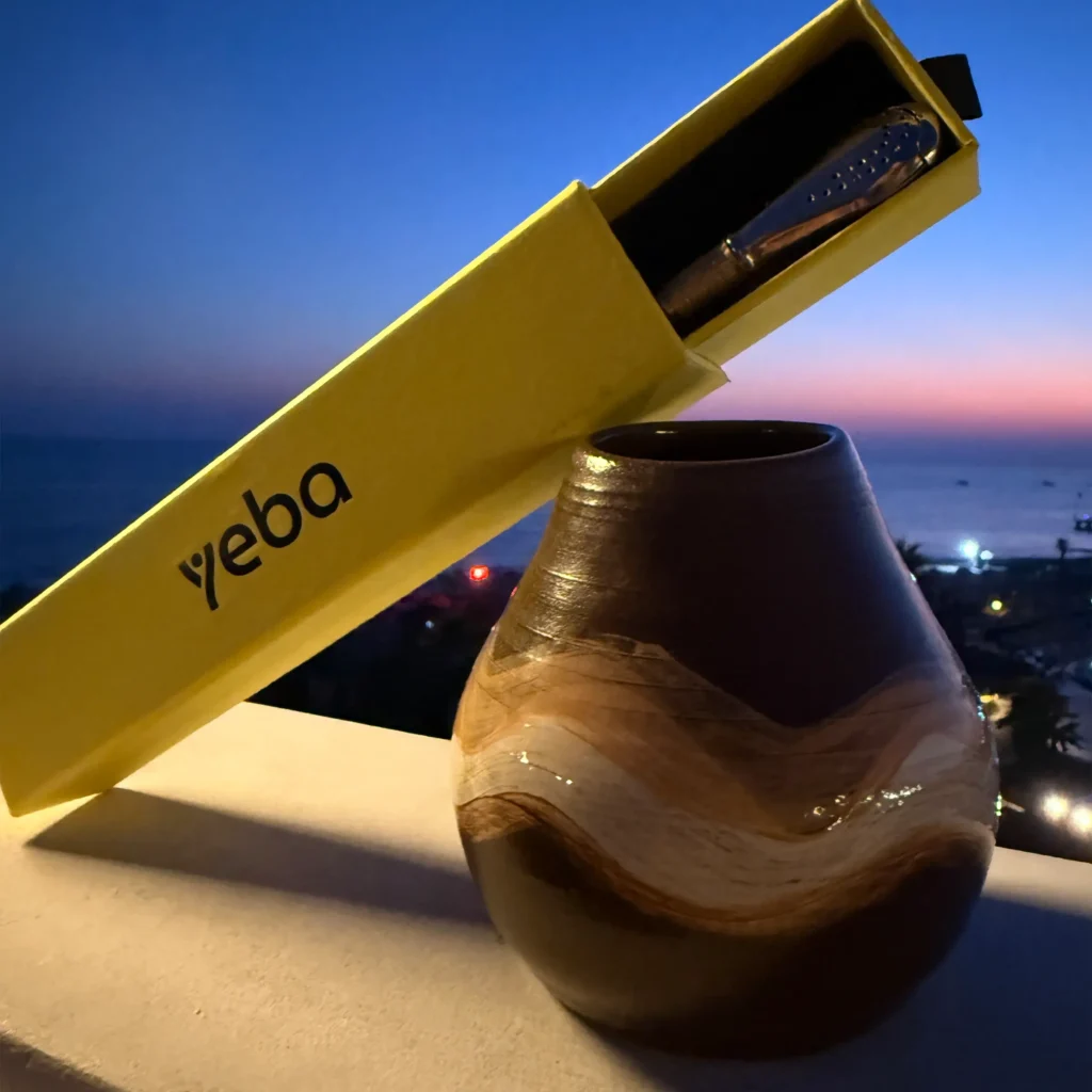 Detail kalabasy Echo s vloženou bombillou a yerba maté pri západe slnka s výhľadom na more.